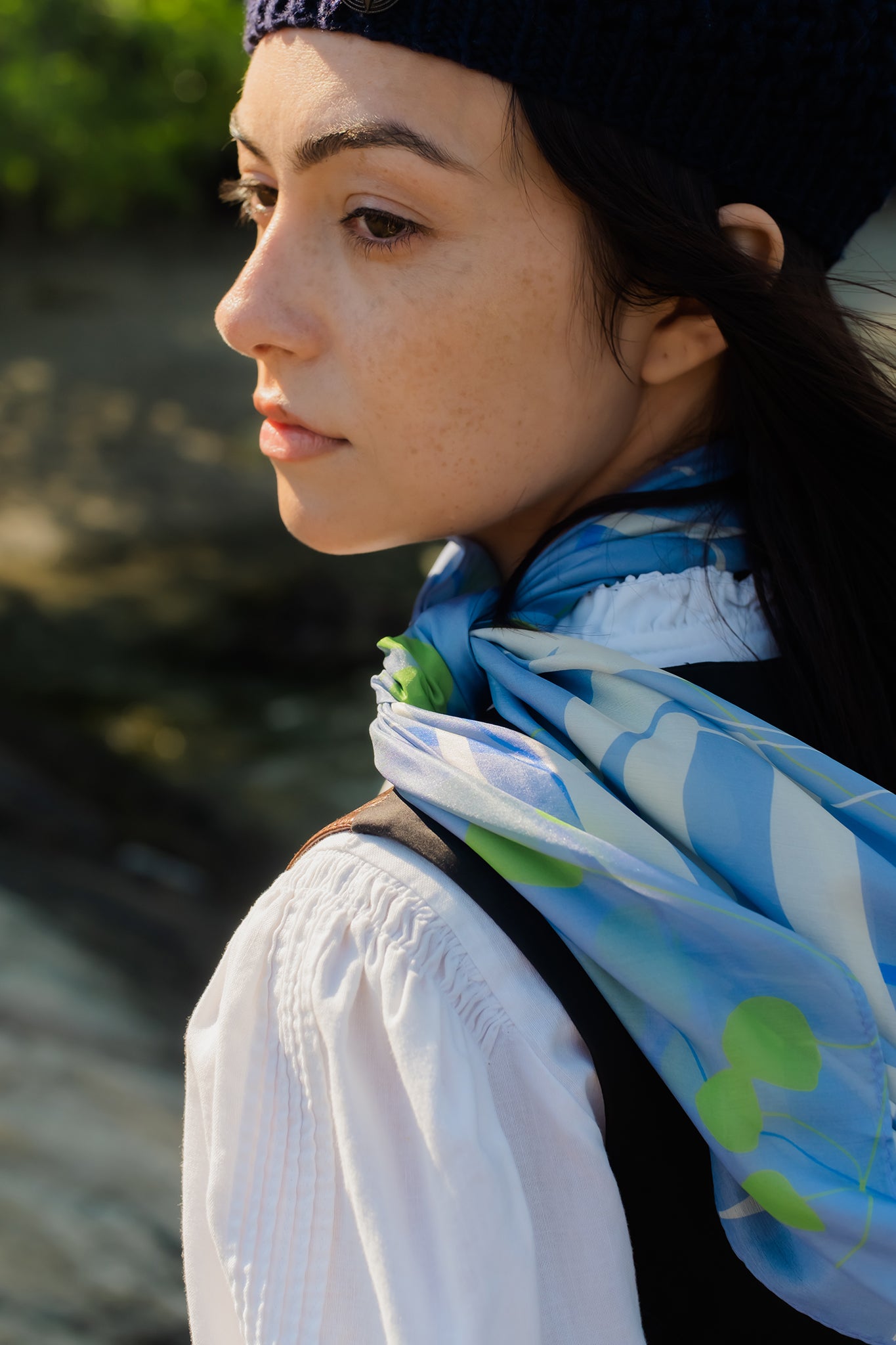 models looks over shoulder while wearing a silk scarf with a finished edge