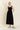 Woman wearing a black sleeveless dress against a beige background