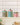Three colorful striped metal spice jars with lids and spherical knobs, displayed on a white shelf against a beige tiled wall.