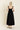 Woman wearing a black dress with thin straps on a beige background