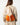 A model wearing an orange and cream colored backpack on a white background. 