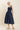 Woman wearing a navy blue dress on a beige background