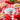 A colorful table setting with fruit, pie, a tin of lip balm on a red and white checkered cloth. 