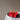 strawberry shaped candle lit on a silver dish with a white background