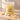 A package of Kolsvart Strömmingen sour lemon candy fish sits on a stone surface with lemon wedges nearby. The clear bag shows yellow sugar-coated fish-shaped candies inside, with the brand name Kolsvart and flavor text printed on the front.