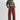 Woman wearing a green cropped sweater and red pants on a white background