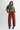 Woman wearing a green cropped sweater and red pants on a white background