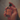 A hand holding a small bottle of dilo Satsuma Oud Eau de Parfum against a warm, softly blurred background.