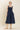 Woman wearing a navy blue dress on a beige background