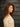 A model wearing a white sweater on a gray background.
