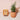 Small terracotta pots with plants on a light pink background. 
