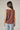 A model wearing a brown and blue plaid sleeveless top on a white background.