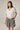 A model wearing a white shirt with checkered shorts on a white background. 