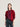 A model wearing a red and black striped knit sweater with a magenta grid pattern panel on the front, paired with dark blue jeans, against a light gray studio background.