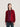 A model wearing a burgundy and red striped crewneck sweater with a magenta grid pattern on the front, paired with dark blue jeans, against a plain off-white background.