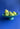 A blue ceramic dish filled with green pear shaped candles on a bright blue background