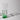 A green glass carafe on a white surface with a gray background