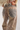 Close-up back view of a person wearing patterned jeans with a brown leather waistband patch embossed with the brand name 'Tach'.