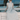 A model wearing a white dress with blue flowers sitting on a boat. 