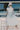 A model wearing a white dress with blue flowers sitting on a boat. 