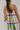 Person wearing a colorful checkered dress with a plain background