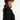 Woman wearing ruffled long sleeved black shirt, with her body facing sideways and her face toward the camera, wearing a brown fur hat on a white background.