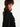 Woman wearing ruffled long sleeved black shirt, with her body facing sideways and her face toward the camera, wearing a brown fur hat on a white background.