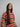 A model wearing a bright colored top on a grey background