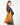 A model wearing a golden colored purse on a grey background. 