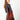 A model wearing a red shoulder bag on a grey background. 
