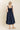 Woman wearing a navy blue dress against a beige background