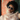 A model wearing a pair of blue clear sunglasses in front of a tile background. 