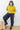 A woman wearing a green sweater and black pants on a white background. 