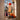 Halloween window decorations displayed on a windowsill with pumpkins. The set includes a black cat doll in a white and black striped outfit, a witch doll in a pink and black diamond-patterned dress, a black cat hanging figure, and a red fuzzy pumpkin ornament.