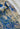 Close-up of a knitted textile with a cream base and blue and green patterned design, folded over to show texture.