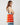 A model wearing a brightly colored shoulder bag on a grey background. 