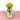 A green and yellow glass vase on a pink surface and white background