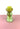 A green and yellow glass vase on a pink surface and white background