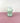 A green glass vase on a pink surface and white background
