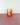 A bright orange striped tumbler on a pink surface with a white background