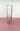 a clear pink vase on a pink surface with a white background