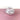 A white and pink vase on a pink surface with a white background