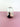 a colorful glass vase on a pink surface with a white background