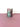 Purple and mint colored tumblers on a pink surface with a white background