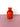 A red vase on a pink surface with a white background