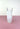 a white glass vase on a pink surface with a white background