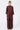 A woman stands against a light gray studio background wearing a matching burgundy two-piece outfit consisting of a long-sleeve button-front shirt and wide-leg pants.
